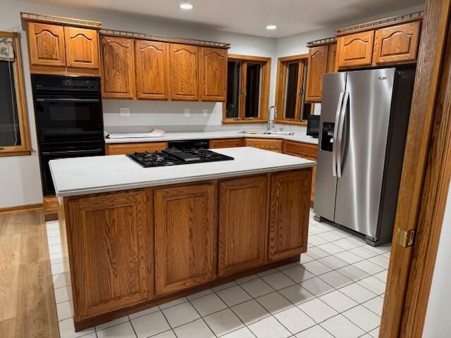 kitchen featuring a center island, sink, light tile patterned floors, and black appliances