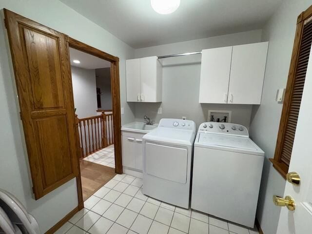 clothes washing area with cabinets, sink, and washer and dryer