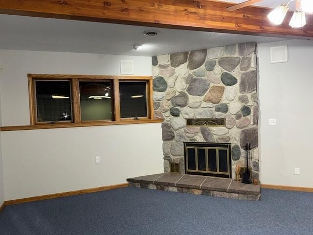 carpeted living room featuring beamed ceiling and a stone fireplace