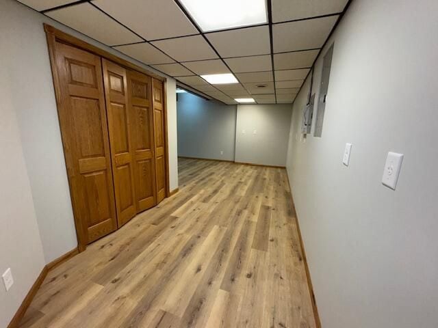 hallway with a drop ceiling and light wood-type flooring