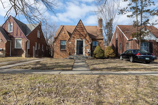 tudor-style house featuring brick siding and a chimney