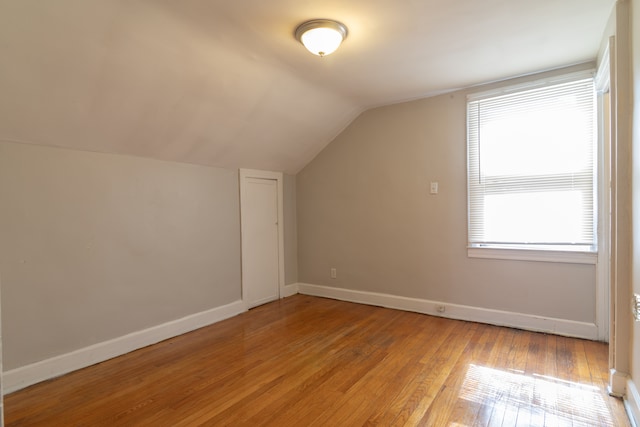 additional living space with lofted ceiling, light wood-style flooring, and baseboards