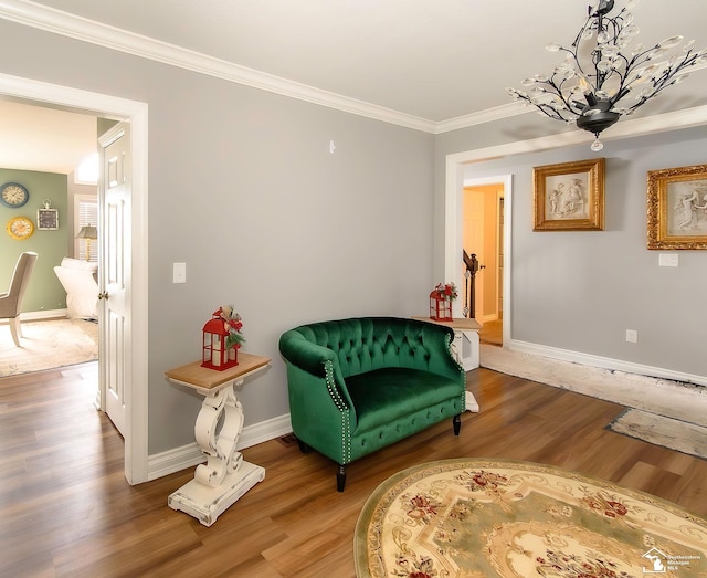 sitting room featuring hardwood / wood-style flooring, crown molding, and a chandelier