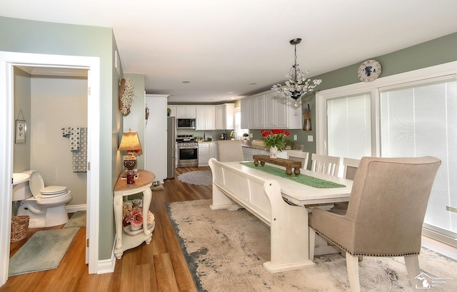 dining room featuring an inviting chandelier, sink, and light wood-type flooring