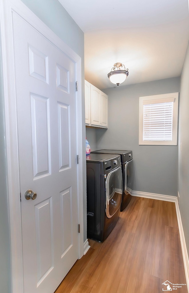 clothes washing area with cabinets, separate washer and dryer, and light wood-type flooring