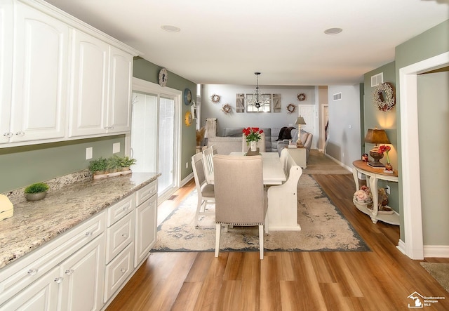 dining space with a notable chandelier and light hardwood / wood-style flooring