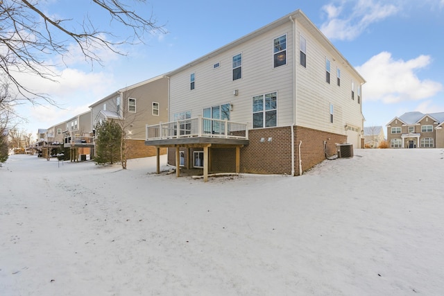 snow covered rear of property with central AC and a wooden deck