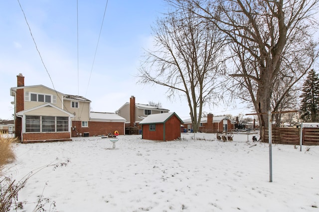 snow covered rear of property featuring a shed