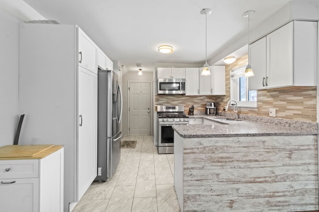 kitchen with pendant lighting, sink, appliances with stainless steel finishes, tasteful backsplash, and white cabinets