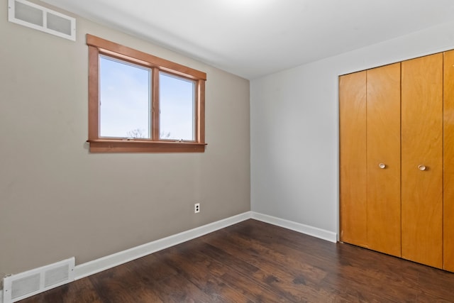 unfurnished bedroom with dark wood-type flooring and a closet