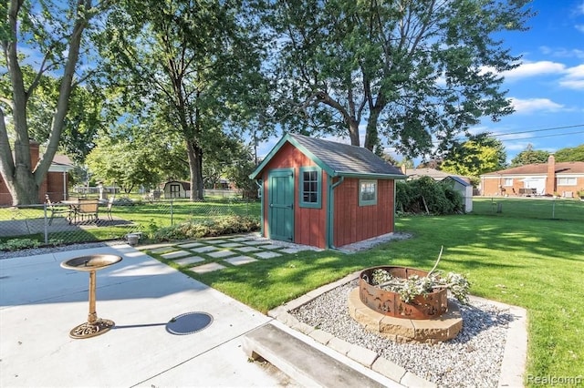 view of outbuilding featuring a lawn and an outdoor fire pit