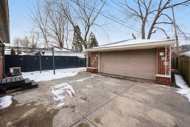 snow covered garage featuring central AC unit