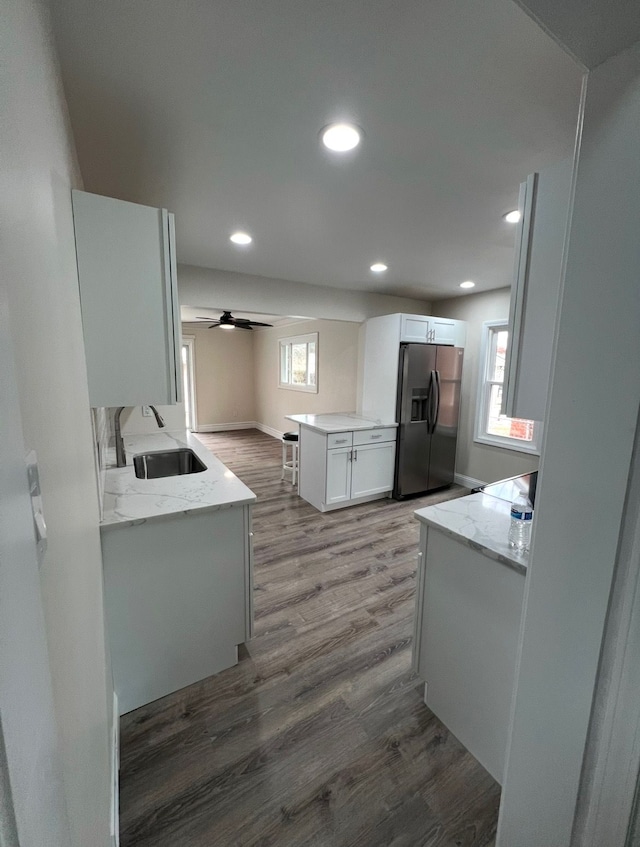 kitchen featuring sink, light stone counters, stainless steel fridge, kitchen peninsula, and white cabinets