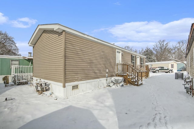 snow covered property with central AC