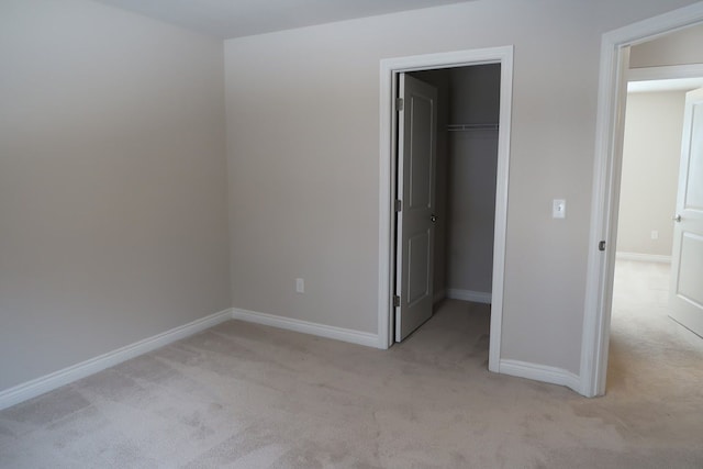 unfurnished bedroom featuring a walk in closet, light colored carpet, and a closet