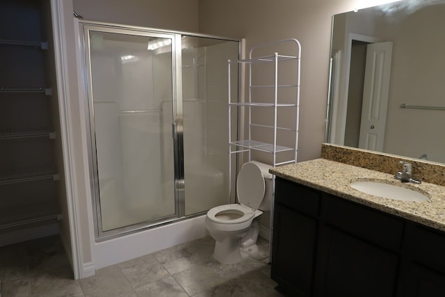 bathroom featuring vanity, toilet, and a shower with door