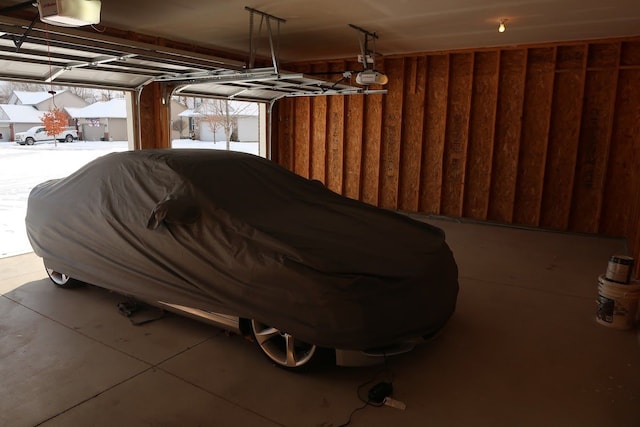 snow covered garage with a garage door opener