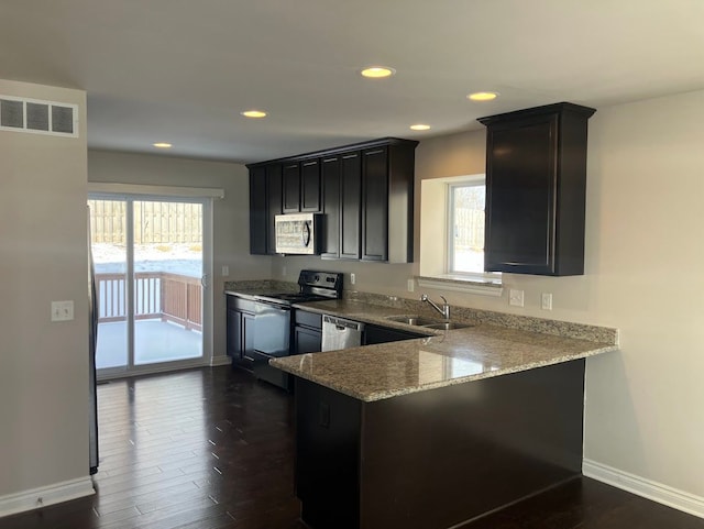 kitchen with stainless steel appliances, sink, a wealth of natural light, and light stone counters