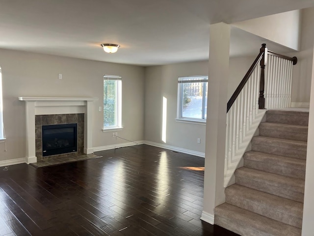 unfurnished living room with a tiled fireplace, dark hardwood / wood-style flooring, and a wealth of natural light