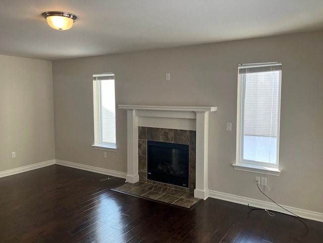 unfurnished living room featuring a tiled fireplace and dark wood-type flooring