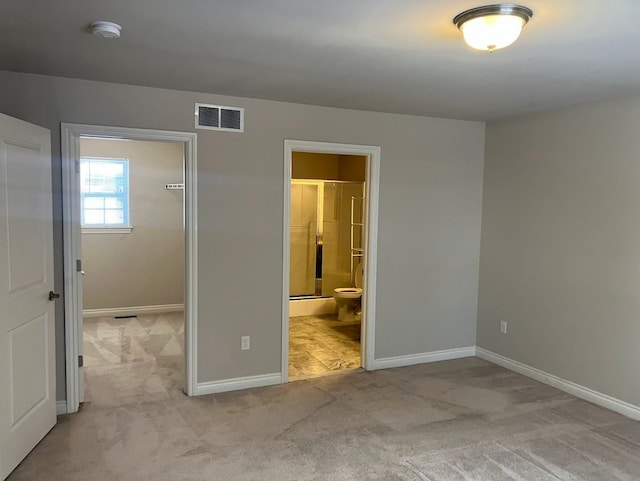 unfurnished bedroom featuring connected bathroom, light carpet, and a spacious closet