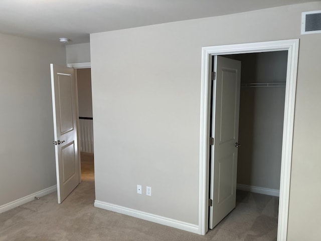 unfurnished bedroom featuring light carpet and a closet