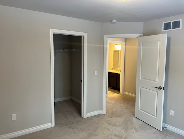 unfurnished bedroom with a spacious closet, light carpet, and a closet