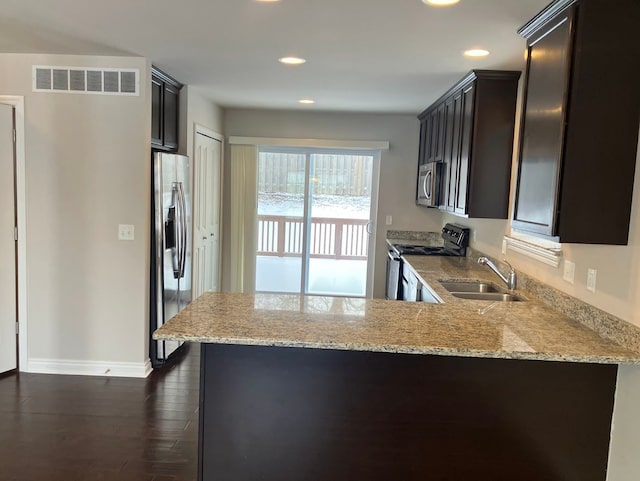 kitchen featuring light stone countertops, appliances with stainless steel finishes, sink, and kitchen peninsula