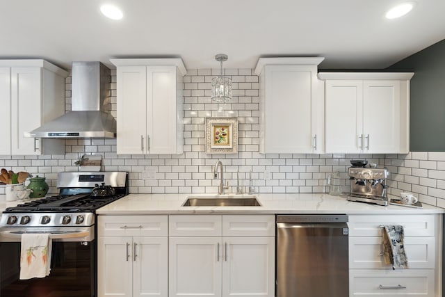 kitchen featuring sink, white cabinetry, tasteful backsplash, appliances with stainless steel finishes, and wall chimney range hood