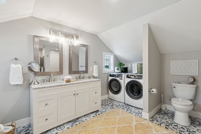 bathroom featuring washing machine and dryer, vaulted ceiling, vanity, and toilet