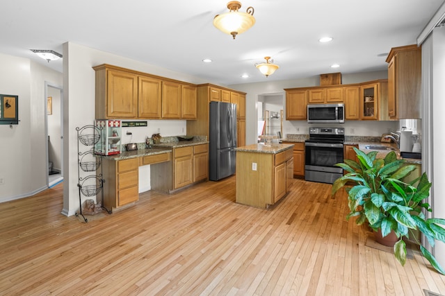 kitchen featuring sink, stainless steel appliances, a center island, light stone counters, and light hardwood / wood-style floors