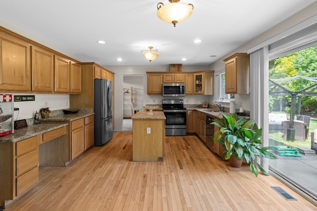 kitchen with light stone counters, sink, a kitchen island, and appliances with stainless steel finishes