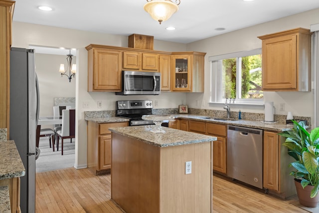 kitchen featuring sink, light stone counters, light hardwood / wood-style flooring, appliances with stainless steel finishes, and a kitchen island