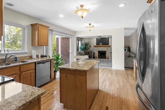 kitchen featuring sink, appliances with stainless steel finishes, a wealth of natural light, a kitchen island, and light wood-type flooring