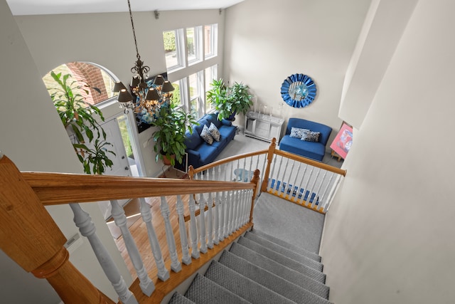 stairway featuring a notable chandelier, carpet floors, and vaulted ceiling