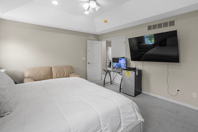 bedroom featuring a tray ceiling, light colored carpet, and refrigerator