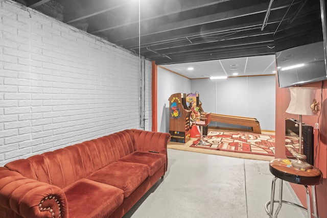 living room featuring brick wall and concrete flooring