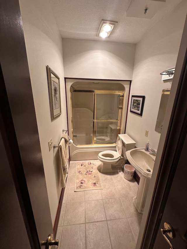 bathroom with toilet, tile patterned floors, shower / bath combination with glass door, and a textured ceiling