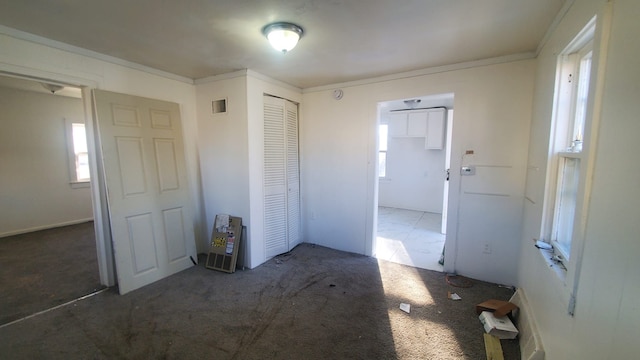 unfurnished bedroom with carpet flooring, a closet, and ornamental molding