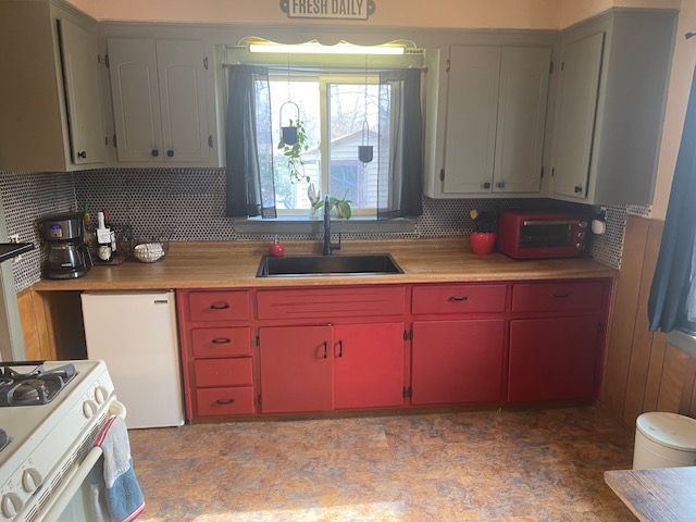 kitchen featuring tasteful backsplash, white gas range oven, sink, and butcher block countertops