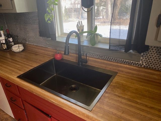 kitchen with butcher block counters, backsplash, and sink