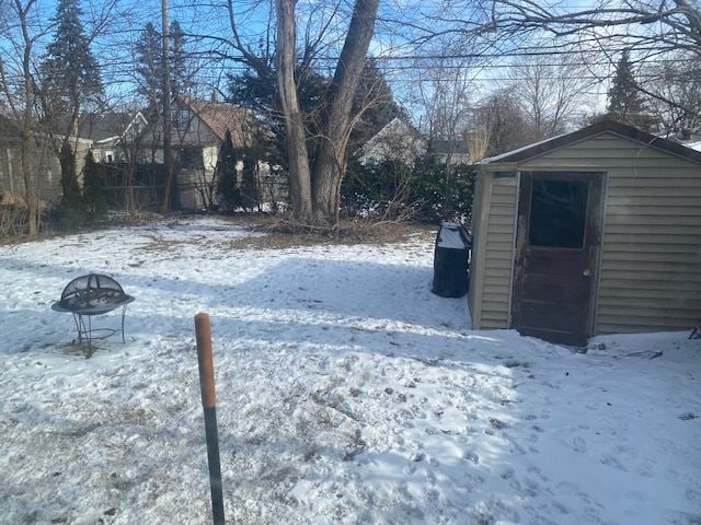 snowy yard featuring a fire pit and a shed