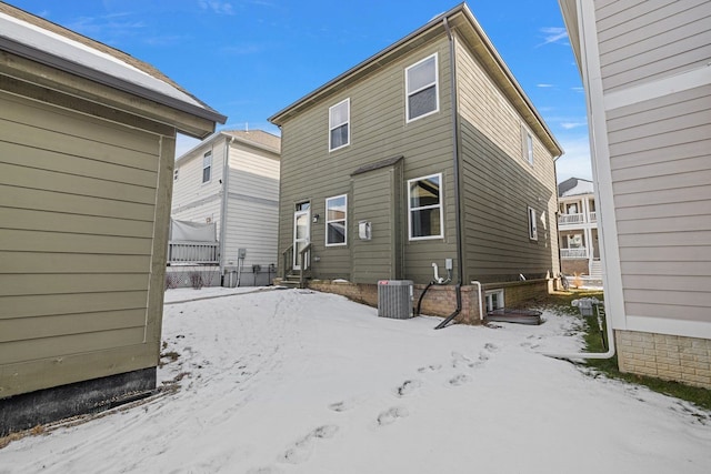 snow covered rear of property featuring central air condition unit