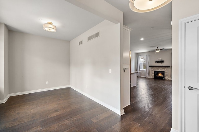 spare room with ceiling fan, dark hardwood / wood-style floors, and a fireplace