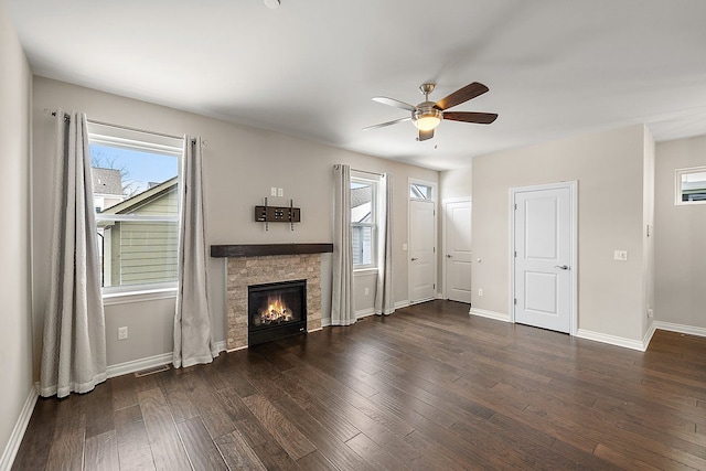 unfurnished living room featuring ceiling fan, dark hardwood / wood-style floors, and a stone fireplace