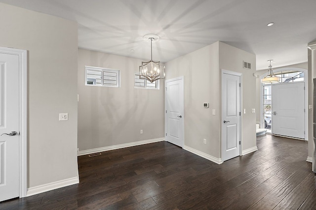 unfurnished dining area with an inviting chandelier and dark hardwood / wood-style flooring