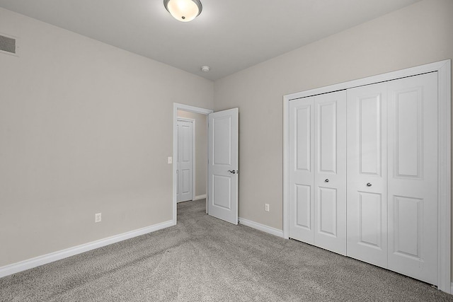 unfurnished bedroom featuring light carpet and a closet