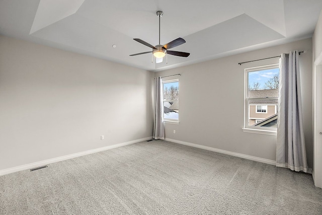 carpeted empty room featuring a tray ceiling and ceiling fan