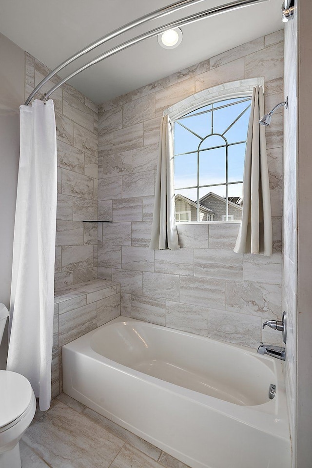 bathroom featuring shower / tub combo and toilet