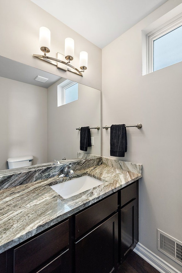 bathroom featuring vanity, a wealth of natural light, and toilet